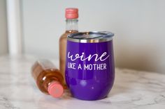 a purple wine tumbler sitting on top of a marble counter next to a bottle