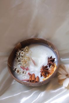 a bowl filled with milk and nuts on top of a white table cloth next to flowers