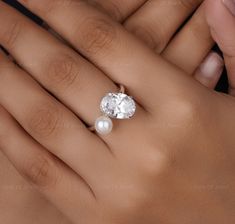 a woman's hand holding an engagement ring with a pearl