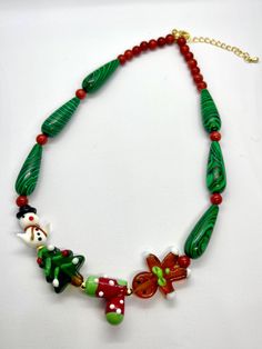 This handmade 38cm Christmas necklace, with a 5cm extension, showcases vibrant coral and malachite beads. Featuring festive glass charms like a gingerbread man, Christmas tree, snowman, and a cute Christmas boot, it's the perfect accessory to add holiday cheer to your look. Christmas Necklaces, Gingerbread Man Christmas Tree, Gingerbread Snowman, Man Christmas Tree, Tree Charms, Christmas Tree Snowman, Gingerbread Man Christmas, Christmas Boots, Tree Snowman