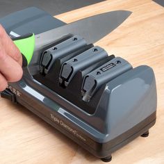 a person using a knife sharpener on a cutting board