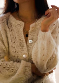 a woman wearing a white sweater and gold necklace