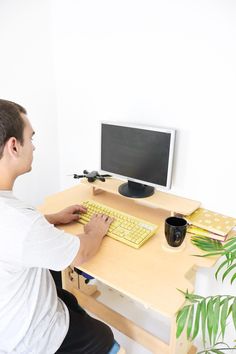 a man sitting at a desk using a keyboard and mouse to work on his computer