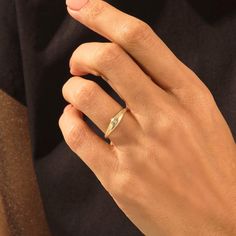 a woman's hand wearing a gold ring with a diamond on the middle finger