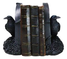 a bookend with two black birds sitting on it's sides and three books in front