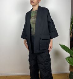 Black Kimono with utility-style cargo pockets. The oversized design is great for layering over jackets, coats and jumpers. It is designed with  ¾ length sleeves and an open front. Made from high-quality sanded canvas from a historic UK company. All fabrics used are 100% plastic-free. This item comes in XS, S, M and L sizes. Please specify which size you would like upon purchase.  Made in East London, UK. Oversized Utility Jacket With Patch Pockets For Work, Oversized Utility Outerwear With Pockets, Oversized Solid Outerwear With Pockets, Black Outerwear With Patch Pockets And Relaxed Fit, Black Relaxed Fit Outerwear With Patch Pockets, Black Relaxed Fit Outerwear With Side Pockets, Spring Techwear Outerwear With Pockets, Oversized Utility Outerwear With Flap Pockets, Oversized Utility Jacket With Pockets