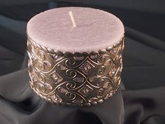 a candle that is sitting on top of a black cloth with gold filigrees