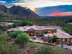 an aerial view of a home in the desert with mountains in the background at sunset