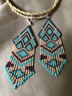 These Native American Inspired, frindge dangle earrings, are multi-colored, and so fluid, easy to move. These are made using a Brick stich in a geometric pattern and then has the pattern continue down in the hanging frindge as well. The beads used are Miyuki Delica beads. The colors are Opaque Turquoise Green, Matte Transparent Mauve, as well as Light Peach Lined bead. These earrings are very colorful and fun! It also has a leverback, antique brass tone earwire, to feel secure. These earrings are 1"inch wide, and 3" inches long, not including the earwire. These can be made in any colors you chose, at no addtional cost or time to you. Thanks so much for looking! Free shipping within the US! Bohemian Blue Geometric Earrings, Handmade Brown Geometric Earrings, Miyuki Delica Beads, Turquoise Green, Delica Beads, Light Peach, Earring Patterns, Brick Stitch, Etsy Earrings Dangle