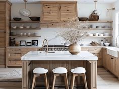 a kitchen with wooden cabinets and white counter tops, three stools in front of the island