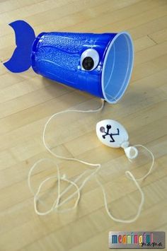 a blue plastic cup sitting on top of a wooden floor next to a pair of headphones