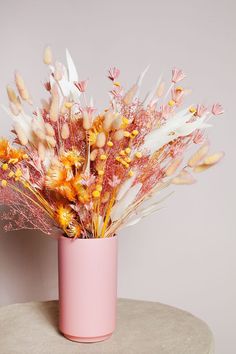 a pink vase filled with flowers on top of a table