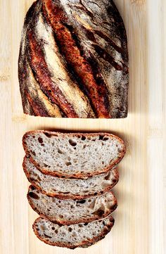 a loaf of bread sitting on top of a cutting board next to slices of bread