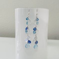 These gorgeous earrings are perfect for someone who loves the color blue. The blue green hues resonate beautifully against each other, creating a mesmerizing color palette. This exquisite collection of gemstones include Sky Blue Topaz, Tanzanite, Natural Chalcedony, Rainbow Moonstone and London Blue Topaz. These gemstones have excellent faceting/polish and clarity. This is a gorgeous suite of high quality gemstone briolettes. The focal sky blue topaz gemstone measures approximately 9½ mm across. Other briolettes range from 5 mm to 8½ mm long. These earrings are completed in sterling silver. The length of the earrings is approximately 2½-inches from the bottom of the earwire. The earrings are finished with fancy sterling silver earwires. Handmade. Find more beautiful styles at my Etsy store Blue Topaz Multi-stone Earrings, Modern Blue Multi-stone Jewelry, Blue Tanzanite Round Earrings, Anniversary Blue Topaz Multi-stone Earrings, Anniversary Multi-stone Blue Topaz Earrings, Modern Blue Earrings With Gemstone Accents, Blue Gemstone Accented Round Earrings, Blue Aquamarine Drop Jewelry, Blue Briolette Earrings Fine Jewelry