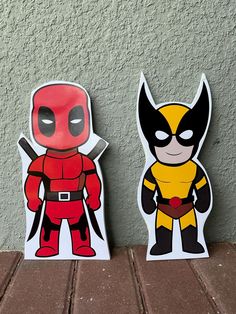 two deadpool stickers sitting next to each other on a brick floor in front of a wall