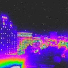 an image of a city at night with buildings in the background and rainbow lights on it