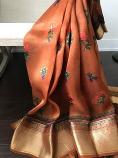 This is a beautiful printed organza saree in earthy brown with beautiful prints all over the body. Blouse has a satin feel with a stone washed look. Saree has floral and fruit prints. Upper narrow border has floral motif and the wider lower border is heavy and grand. Zari borders gives a good contrast to brown body. Last picture shows the blouse piece  * Colour may vary slightly due to lighting  * Handloom products may have slight irregularities * All sales are final * No falls or pico done * Maintenance: Dry clean only Organza Banarasi Saree, Body Blouse, Fruit Prints, Sabyasachi Sarees, Kora Silk Sarees, Printed Organza, Grey Saree, Saree Floral, Bridesmaid Saree