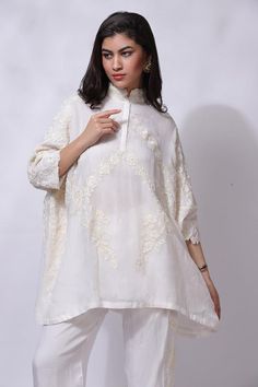 White aari hand embroidered pocho style tunic. Paired with a matching pant.
Components: 2
Pattern: Embroidered
Type Of Work: Aari
Neckline: High collar
Sleeve Type: Three-quarter
Fabric: 50% Silk, 50% Cotton
Color: White
Other Details: 
Attached cotton lining
Closure: Hook and Eye
Occasion: Resort - Aza Fashions Eid Tunic Palazzo Set With Chikankari Embroidery, Eid Chikankari Embroidered Tunic Palazzo Set, Chikankari Embroidery Tunic For Wedding, Designer Chikankari Embroidery Tunic, Chikankari Embroidery Tunic, Long Sleeve Resham Embroidered Tunic For Wedding, Wedding Tunic With Chikankari Embroidery, Long Sleeve Resham Embroidery Tunic For Wedding, Long Sleeve Tunic With Resham Embroidery For Wedding