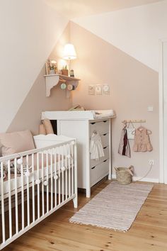 a baby's room with a white crib, dresser and bed in it