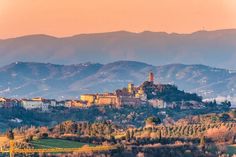 a small town on top of a hill with mountains in the background