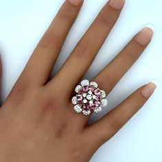 a woman's hand with a pink and white diamond ring on top of it