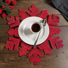 a white plate topped with a cup of coffee next to a red snowflake