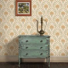 an old dresser in front of a wallpapered room with a painting on the wall