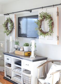 a tv mounted to the side of a wall next to a table with baskets on it