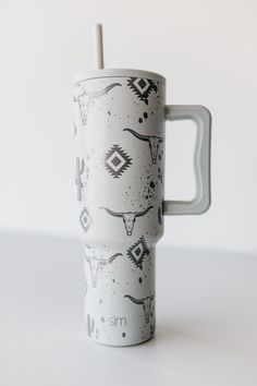 a white coffee cup with an animal pattern on it and a straw sticking out of the lid