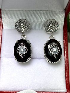 Faux Black Onyx Solid Sterling Silver Earrings Edward Embellished Design#E70e This is a pair of antique-inspired Edwardian style earrings. The flawless oval simulated black onyx gems are surrounded by delicate sterling silver filigree. The lovely full cut oval stones are approximately 14mm x 10mm. In the middle of each earring there lies delicate filigree surrounding a centered inset gem. Please choose white CZ (cubic zirconia), Lab Moissanite, or genuine diamond for the inset gem. The earrings Black Oval Filigree Jewelry, Oval Black Filigree Jewelry, Classic Black Oval Earrings, Antique Black Pierced Earrings, Black Oval Vintage Earrings, Vintage Black Oval Earrings, Antique Black Earrings For Gift, Black Onyx Oval Earrings, Antique Style Black Earrings For Gift