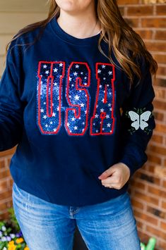 Sparkle with pride in our USA Glitter Appliqué Embroidered Navy Crewneck Sweatshirt! Made with high-quality materials, this sweatshirt features a bold and eye-catching design that showcases your American spirit. Stay cozy and stylish while showing your love for the USA. Inspire others with your patriotic look today! This is a physical product, This product contains glitter HTV. This product is embroidered. This product is unisex. Trendy French Terry Tops For College, Glitter Print Crew Neck Tops For Fall, Blue Embroidered T-shirt For Fall, Crew Neck Top With Glitter Print For Fall, Long Sleeve Cotton Tops With Glitter Print, Casual Tops With Glitter Print For Streetwear, Long Sleeve Cotton Sweatshirt With Glitter Print, Trendy Long Sleeve Top With Embroidered Logo, Casual Long Sleeve Sweatshirt With Glitter Print