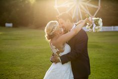 the bride and groom are embracing in front of a ferris wheel