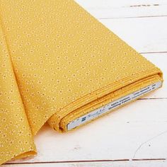 a close up of a yellow fabric on a white wooden surface