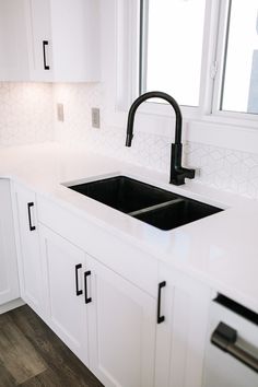 a kitchen with white cabinets and black faucet