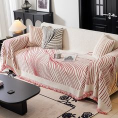 a living room with a white couch covered in a red and black striped blanket next to a coffee table