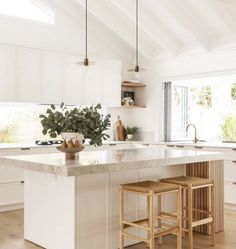 a kitchen with two stools next to an island in the middle of the room