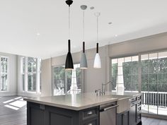 a kitchen with an island and three pendant lights hanging from it's ceiling over the sink