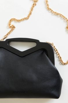 A staple handbag to add to your collection. The Black Triangle Handle Point Bag is made with a magnetic frame, v handle and a gold chain strap to wear on shoulders. The crossbody bag features one zip pocket and two slot pockets. Wear the black chain crossbody bag from everyday wear to special occasions. Luxury vegan leather 12"W x 6.5"H x 2.5"D Handle Drop: 3" Strap Length: 43" Magnetic Closure Gold-Tone Hardware Interior Zip & Slot Pockets Cotton Lining Fits up to an iPhone 11 Pro Max Modern Black Evening Bag With Chain Strap, Everyday Shoulder Clutch With Chain, Evening Pouch Satchel With Chain Strap, Evening Satchel With Chain Strap In Pouch Shape, Evening Satchel With Chain Strap And Pouch Shape, Chic Black Clutch With Top Carry Handle, Evening Satchel With Chain Strap Pouch, Black Handheld Clutch With Gold-tone Hardware, Black Clutch With Gold-tone Hardware