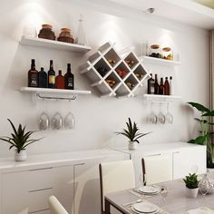 a dining room table with white chairs and wine bottles on the wall above it,