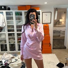 a woman taking a selfie while wearing a pink bathrobe in her bedroom