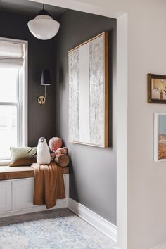 a window seat with stuffed animals on it in front of a painting and framed pictures