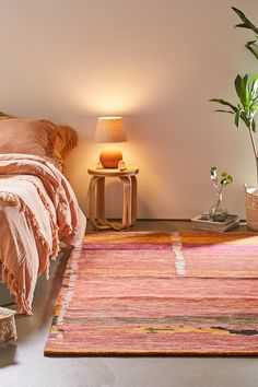 a room with a bed, lamp and rug on the floor in front of it