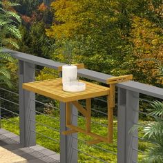 a wooden table sitting on top of a balcony next to a lush green forest filled with trees