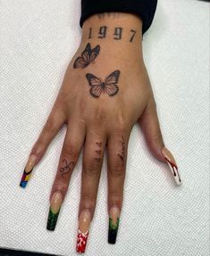 a woman's hand with butterflies on it and numbers painted on the fingers,