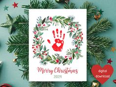 a christmas card with a handprinted heart and holly wreath surrounded by other holiday decorations