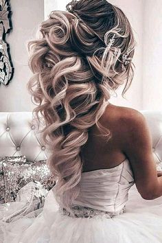 a woman in a wedding dress sitting on a couch with her hair curled up into a ponytail