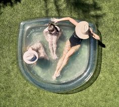 two people in a pool with hats on their heads and one person laying down wearing a hat