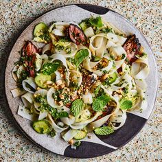 a plate filled with pasta, broccoli and nuts