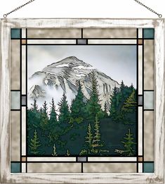 a stained glass window with a mountain scene in the middle and pine trees on both sides