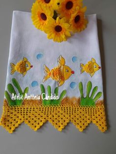 yellow flowers are sitting on top of a white table cloth with fish and plants painted on it